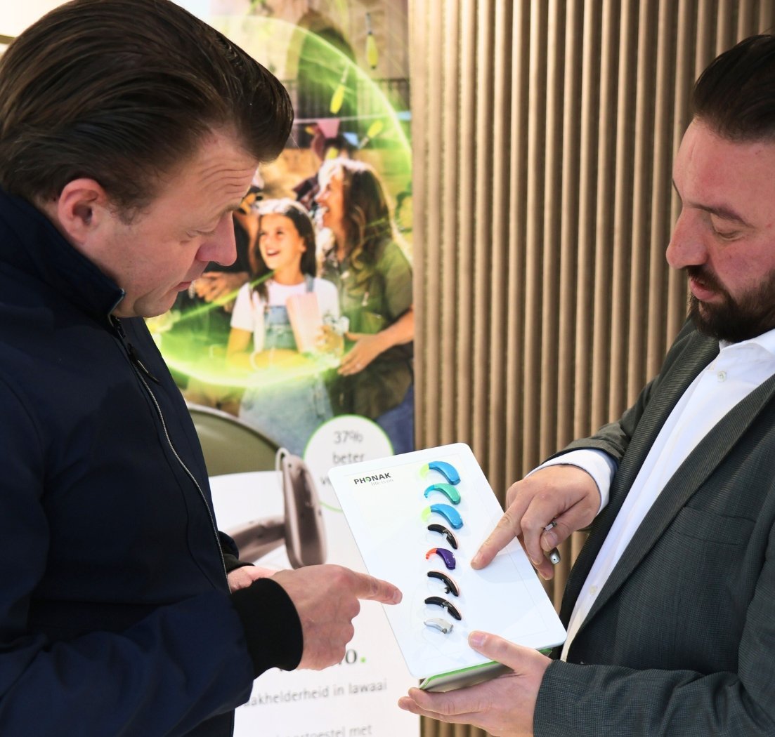 Een klant en medewerker vergelijken hoorapparaten in de praktijk