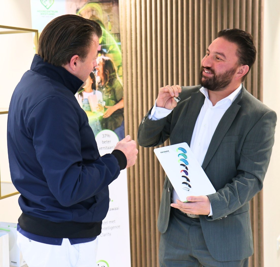 Een medewerker bespreekt hoortoestellen met een klant in de praktijk