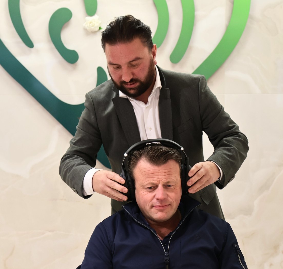 Een medewerker plaatst een hoofdtelefoon bij een klant voor gehooronderzoek